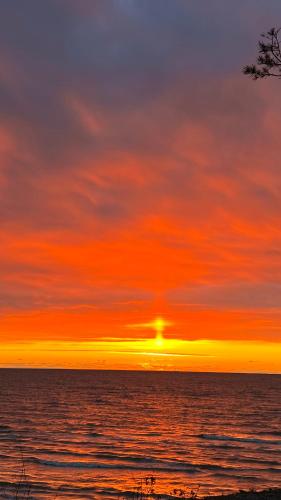 un tramonto sull'oceano con il sole nel cielo di Little Amber a Bernāti