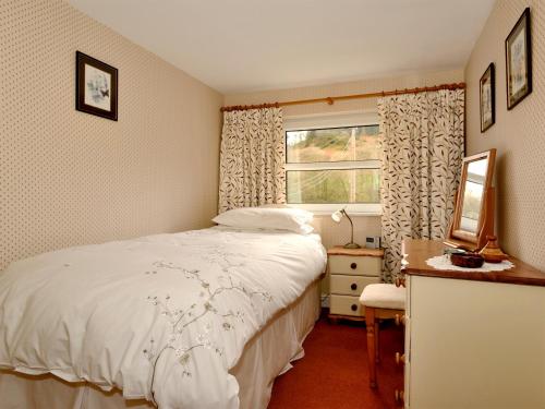 Schlafzimmer mit einem Bett und einem Fenster in der Unterkunft Mollys Cottage in Glenridding