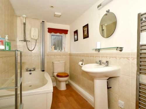 y baño con lavabo, aseo y espejo. en Mollys Cottage, en Glenridding