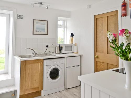 a kitchen with a washing machine and a sink at Shore Cottage in Carsluith