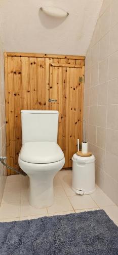 La salle de bains est pourvue de toilettes blanches et d'un mur en bois. dans l'établissement Peloponnese Hideout - White house with the sea view, à Akrata