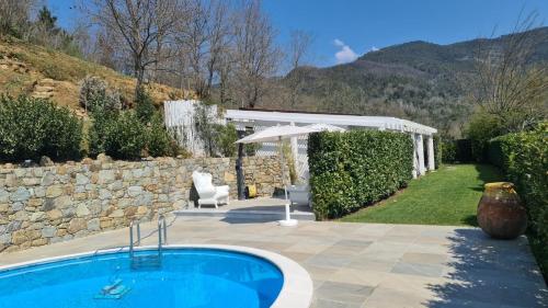 a swimming pool in a garden with an umbrella and a patio at Orchidea in Beverino