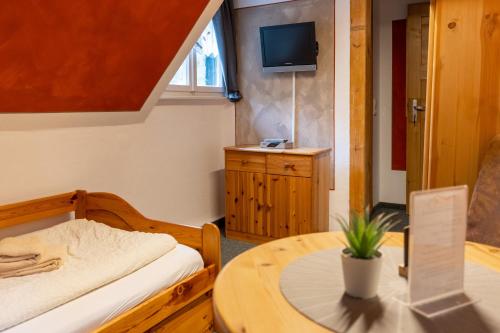 a room with a bed and a table and a tv at Pension Schrammsteinbaude in Bad Schandau