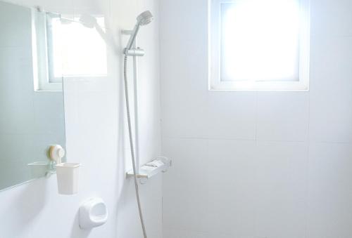 biała łazienka z prysznicem i oknem w obiekcie RedDoorz at Caree Boutique Hotel Bulan Sorsogon w mieście Bulan