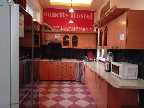 a kitchen with wooden cabinets and a red sign at Sun city hostel in Yerevan