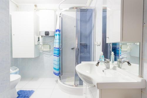 a white bathroom with a shower and a sink at Visegrád Vendégház-Apartman in Visegrád
