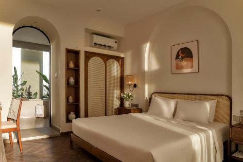 a bedroom with a bed and a table and a chair at RUBENS BOUTIQUE HOTEL in Phan Thiet