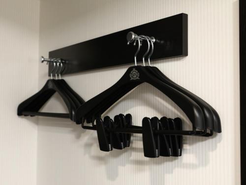 a black rack with three black hangers on a wall at APA Hotel Kobe Sannomiya in Kobe