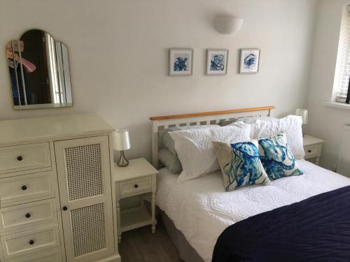 a bedroom with a bed and a dresser and a mirror at Stunning Compact Apartment Just Outside Looe in Torpoint