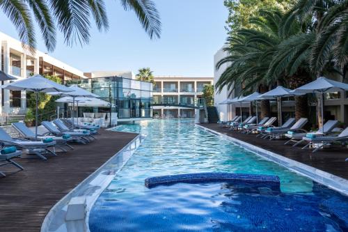 a swimming pool with chairs and umbrellas at a resort at Minos Mare Royal in Platanes