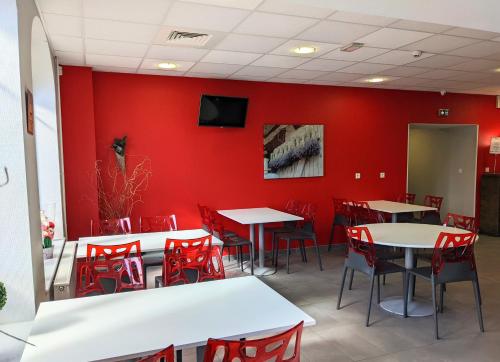 ein Esszimmer mit roten Wänden, Tischen und roten Stühlen in der Unterkunft Auberge des Remparts in Péronne