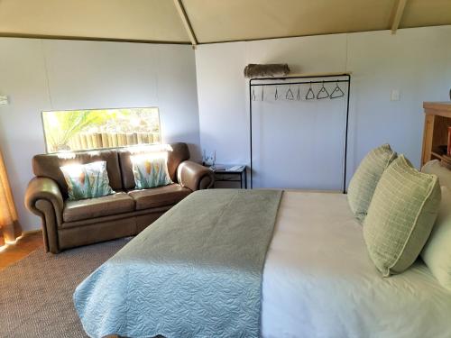 ein Schlafzimmer mit einem großen Bett und einem Sofa in der Unterkunft Glamping at The Well in Franschhoek in Franschhoek