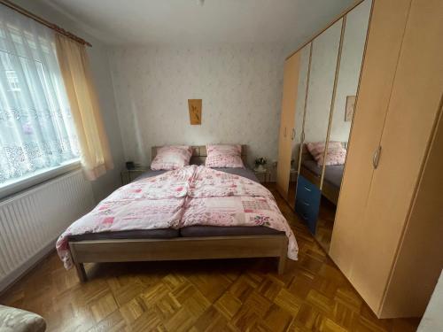 um quarto com uma cama com um edredão rosa em Ferienwohnung Beer em Fehrenbach
