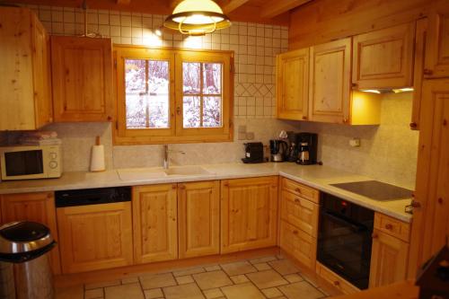 a kitchen with wooden cabinets and a window at Chalet Le Sabot De Venus in Combloux