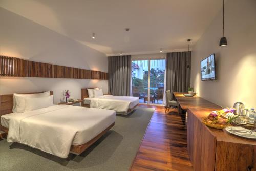 une chambre d'hôtel avec deux lits et un bureau dans l'établissement Hotel Somadevi Angkor Boutique and Resort, à Siem Reap