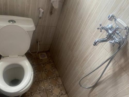 a bathroom with a toilet with a hose next to it at Single Bedroom Sitting Room in Kampala