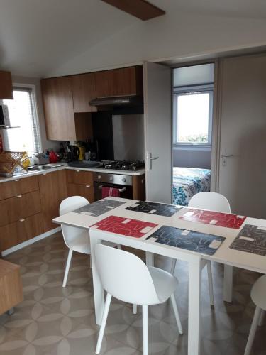 - une cuisine avec une table blanche et des chaises blanches dans l'établissement le logis de la girafe, à Litteau