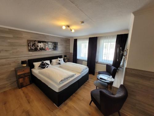 een slaapkamer met een groot bed en een stoel bij Hotel MoinMoin in Bad Bramstedt