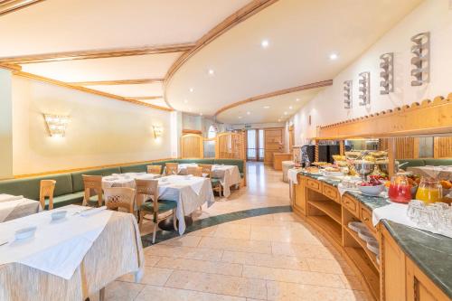 ein Restaurant mit Tischen und Stühlen und einem Buffet in der Unterkunft Hotel Relais Orsingher in Fiera di Primiero