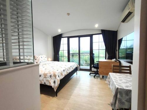 a bedroom with a bed and a desk and a window at Venetian Signature Condominium in Jomtien Beach