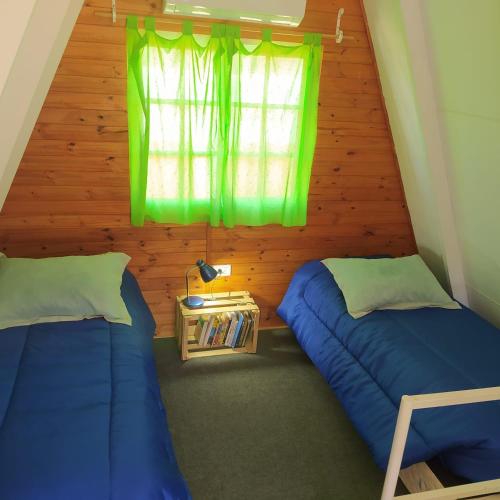 two beds in a small room with a window at Cabañas en Koslay Ñalala Ivoqué con piscina climatizada en épocas cálidas in Juana Koslay 