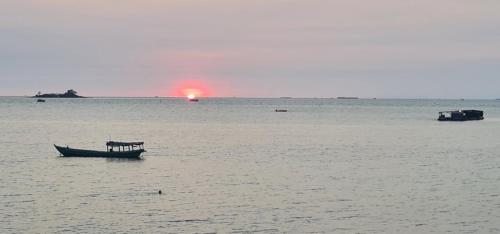 a boat in the water with the sunset in the background at BREAKING DAWN- TAEYANG Hotel Phú Quốc in Phu Quoc
