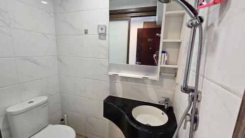 a bathroom with a toilet and a sink and a mirror at Apartement Sky House BSD By LiviRooms in Tjilandak