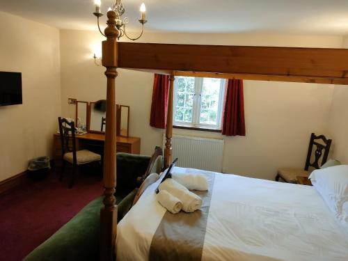 a bedroom with a four poster bed and a desk at Great Trethew Hotel - Self Catering Lodges - Bar & Restaurant in Liskeard