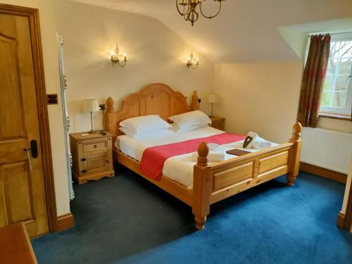 a bedroom with a large bed with a wooden headboard at Great Trethew Hotel - Self Catering Lodges - Bar & Restaurant in Liskeard