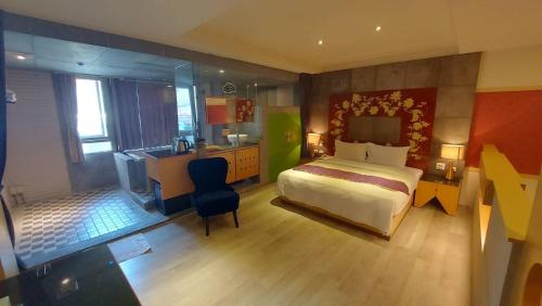 a bedroom with a bed and a desk and a kitchen at Jungle City Motel in Chiayi City