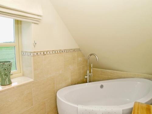 a white bath tub in a bathroom with a window at Wandale Barn in Slingsby