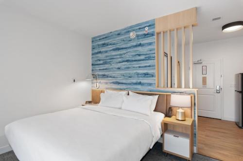 um quarto com uma cama branca e uma pintura azul na parede em TownePlace Suites by Marriott White Hall em White Hall
