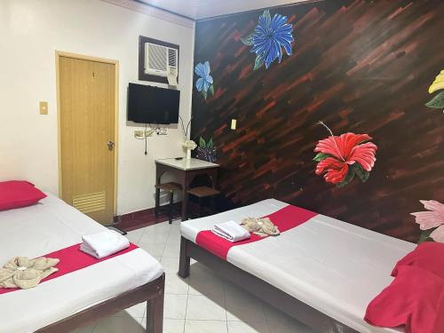 Zimmer mit 2 Betten mit Blumen an der Wand in der Unterkunft RedDoorz at Kaffe De Oro Hotel Socorro Oriental Mindoro in Socorro