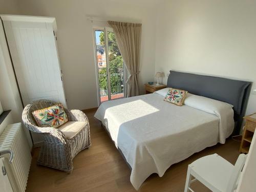 a bedroom with a bed and a chair and a window at Attico Fronte Mare nel Borgo di Celle Ligure in Celle Ligure