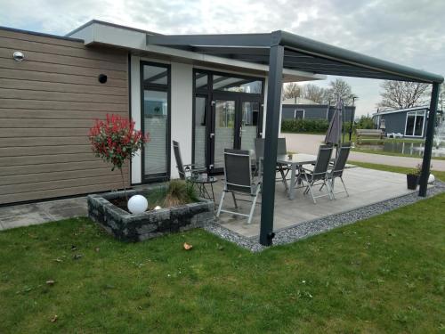 a pavilion with chairs and a table in a yard at Ferienhaus / Chalet / Bungalow am See, Holland, Niederlande, Lathum in Lathum