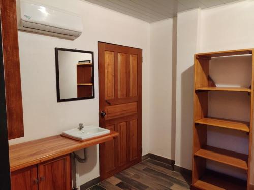 a bathroom with a sink and a wooden door at Cabinas Pura Vida B&B Tour Operator in Drake