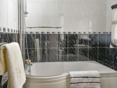 Heighington的住宿－North Cottage，浴室设有白色浴缸和黑色瓷砖。
