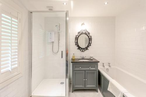 a bathroom with a shower and a sink and a mirror at The Stable - cottage with a spectacular lake view in Port of Menteith