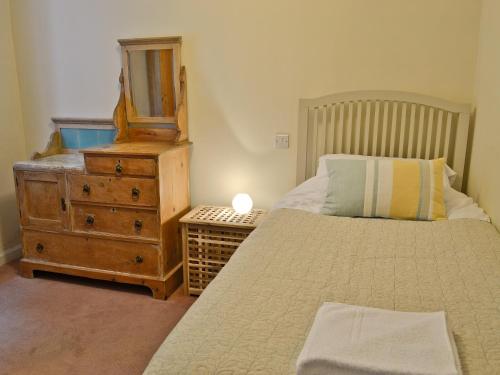 a bedroom with a bed and a dresser with a mirror at Dylasau Cottage in Capel Garmon