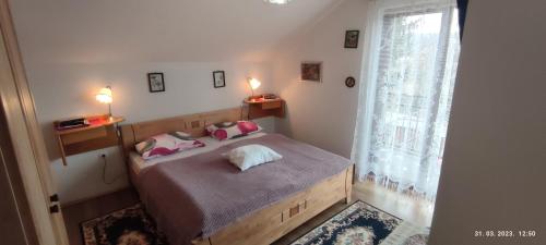 Schlafzimmer mit einem Bett mit rosa Kissen und einem Fenster in der Unterkunft LiamMarco in Plaški
