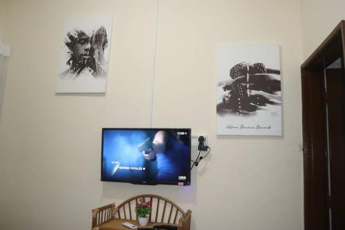 a flat screen tv hanging on a wall with pictures at Studio Yiri Guest 1 Fidjrossè Plage in Cotonou
