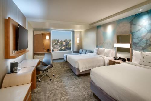 a hotel room with two beds and a flat screen tv at Courtyard by Marriott Los Angeles LAX/Hawthorne in Hawthorne