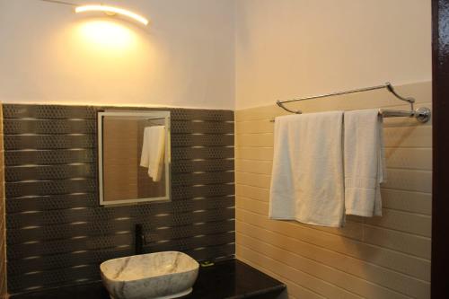 a bathroom with a sink and a mirror and towels at Green Reed Resort By Meenakshi, Kaziranga in Hatikhuli