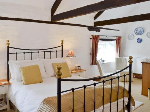 a bedroom with a bed and a desk with a lamp at Yet Farm Cottage in Cenarth