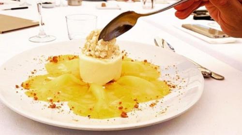 a person eating a dessert on a plate with a spoon at Hotel Donibane Saint-Jean-de-Luz in Saint-Jean-de-Luz