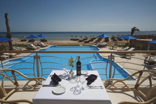 a table with a bottle of wine next to a pool at Shams Prestige Abu Soma (Adults Only) in Hurghada