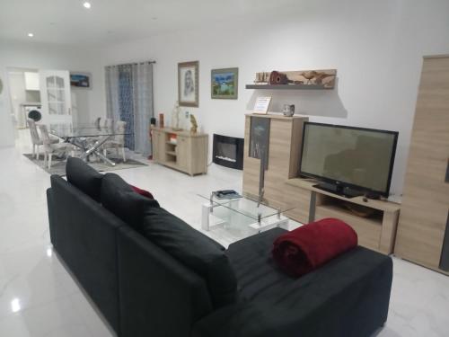 a living room with a black couch and a television at Casa da Linda in Ponta Delgada