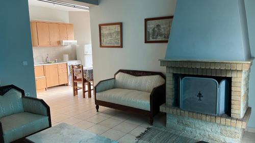 a living room with a fireplace with a couch and chairs at Kanalis Houses in Avlonárion