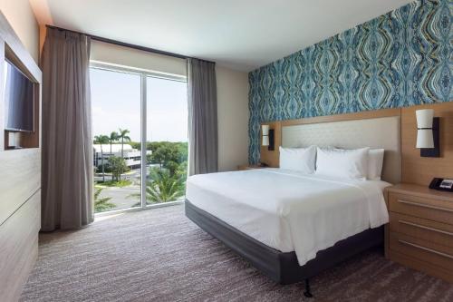 a hotel room with a bed and a large window at Residence Inn Palm Beach Gardens in Palm Beach Gardens