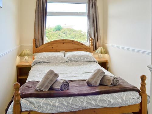 1 dormitorio con 1 cama con 2 almohadas y ventana en Fairlawns, en Fairbourne